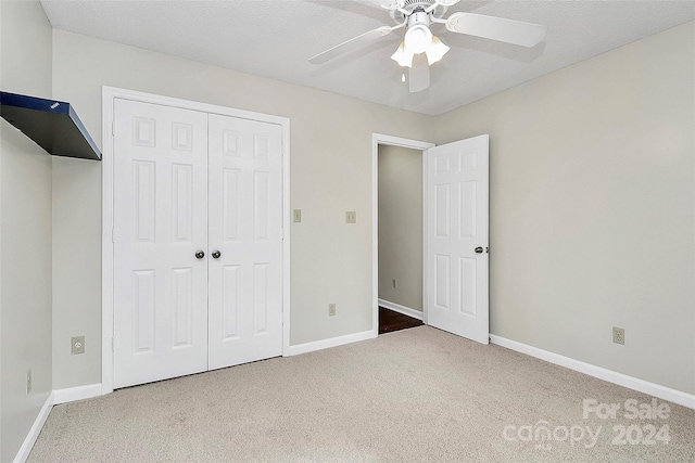 unfurnished bedroom with a textured ceiling, carpet floors, ceiling fan, and a closet