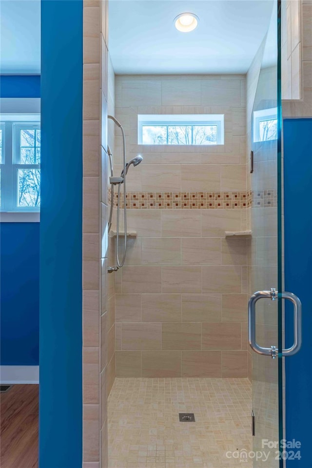 bathroom with wood-type flooring and a shower with door