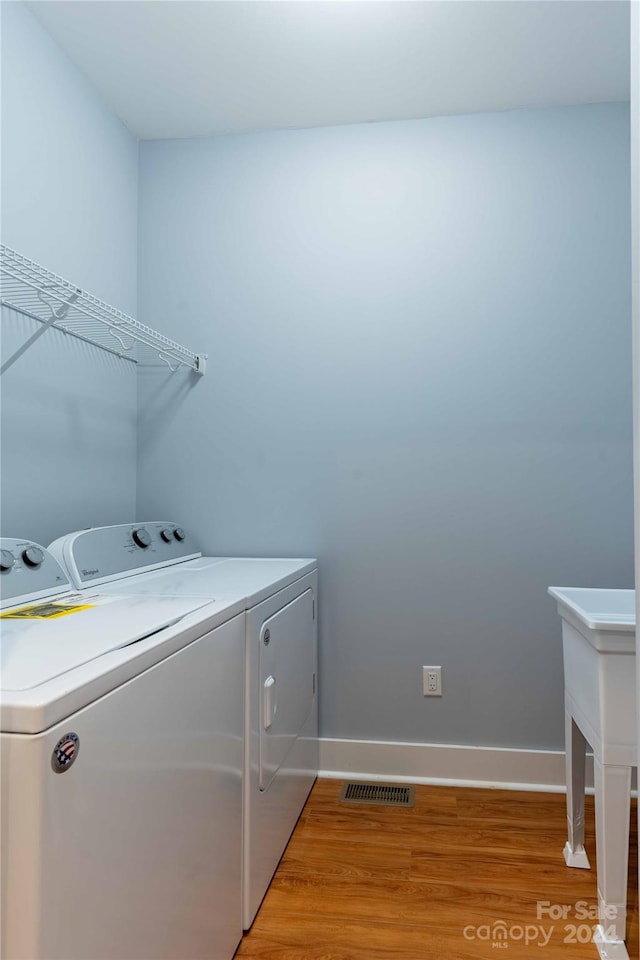 laundry area featuring washing machine and dryer and light wood-type flooring