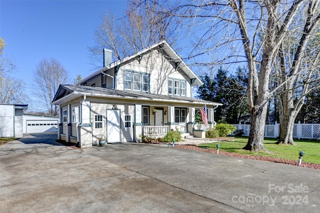 view of front of home featuring a front yard, a garage, an outdoor structure, and a porch