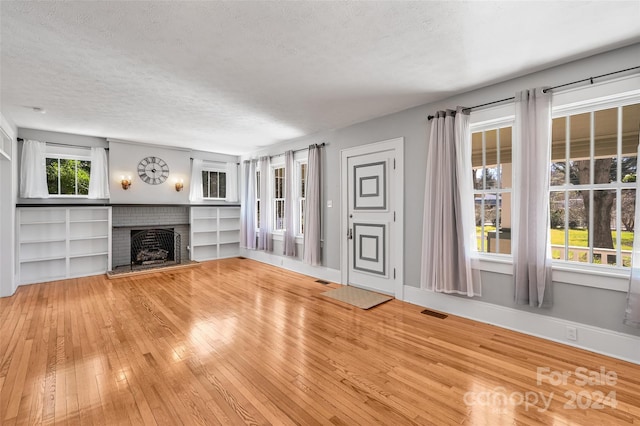 unfurnished living room featuring a fireplace, wood-type flooring, and a textured ceiling