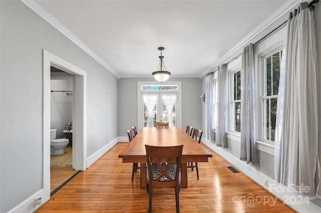 dining room with a wealth of natural light, light hardwood / wood-style floors, and crown molding