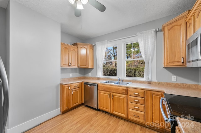 kitchen with a textured ceiling, sink, light hardwood / wood-style flooring, and appliances with stainless steel finishes