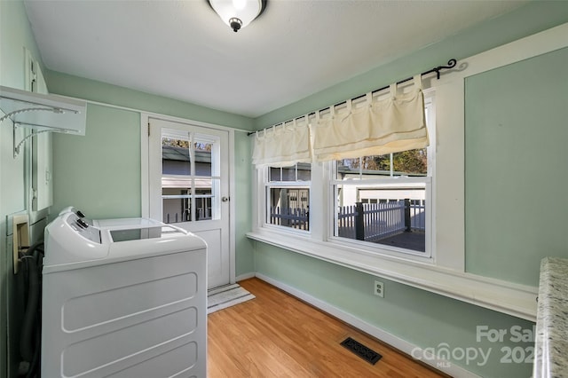 washroom featuring washing machine and clothes dryer and light hardwood / wood-style flooring