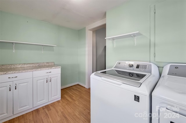 clothes washing area with cabinets, light wood-type flooring, and washer and clothes dryer