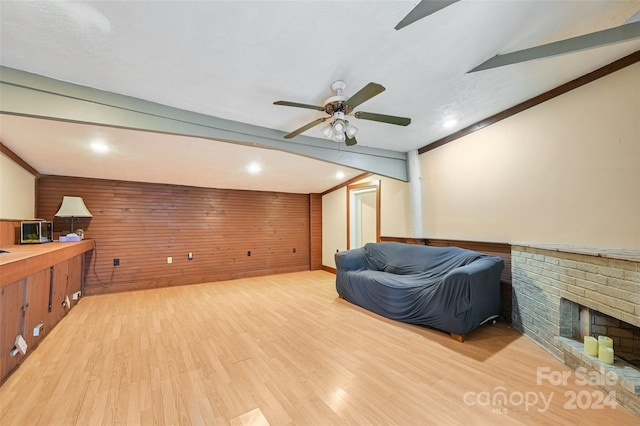 sitting room with wood walls, light wood-type flooring, vaulted ceiling, and ceiling fan