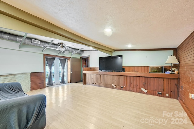 living room with light wood-type flooring, wooden walls, ceiling fan, and beam ceiling