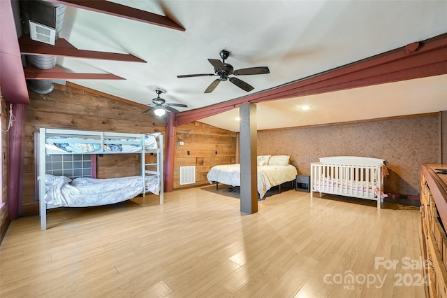 unfurnished bedroom featuring wood walls, light hardwood / wood-style floors, ceiling fan, and lofted ceiling