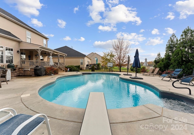 view of swimming pool with a diving board and a patio area