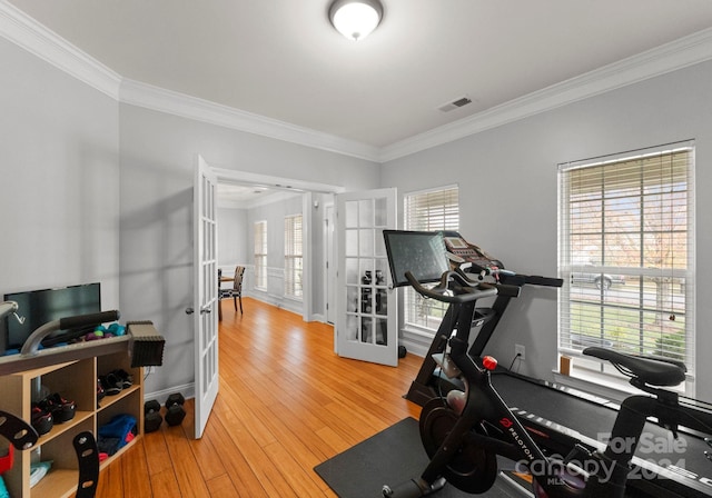 exercise room featuring ornamental molding, a wealth of natural light, hardwood / wood-style flooring, and french doors