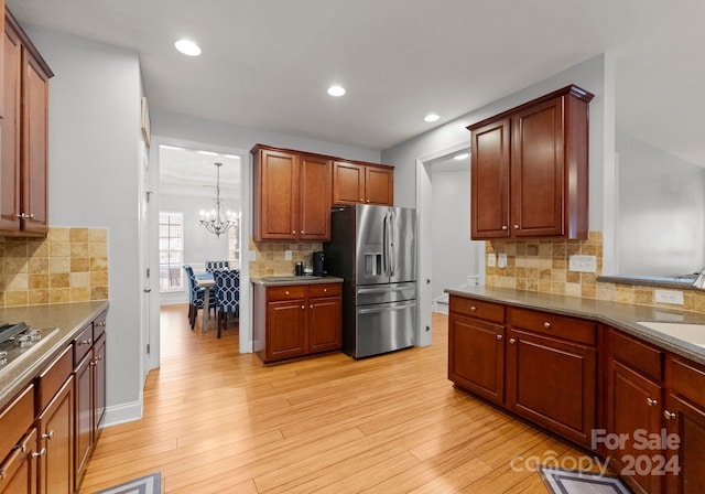 kitchen with stainless steel fridge, backsplash, light hardwood / wood-style flooring, and a notable chandelier