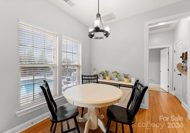 dining area with hardwood / wood-style floors and a notable chandelier