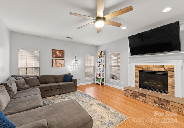 living room with a fireplace, hardwood / wood-style flooring, ceiling fan, and a healthy amount of sunlight