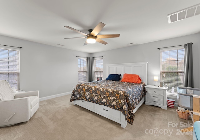 bedroom with ceiling fan, multiple windows, and light colored carpet