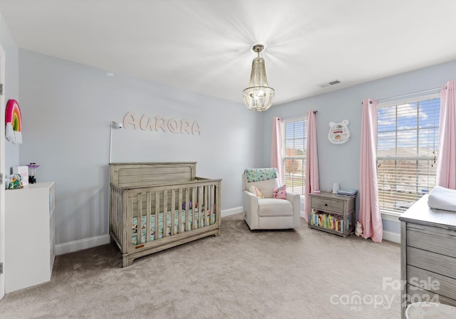 carpeted bedroom with a crib and a notable chandelier