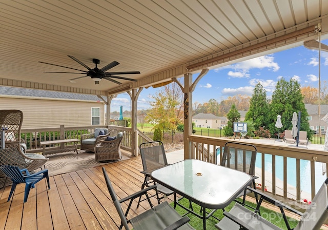 wooden terrace with an outdoor living space, a water view, ceiling fan, and a beach view