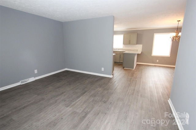 unfurnished living room with dark hardwood / wood-style flooring, a textured ceiling, and an inviting chandelier