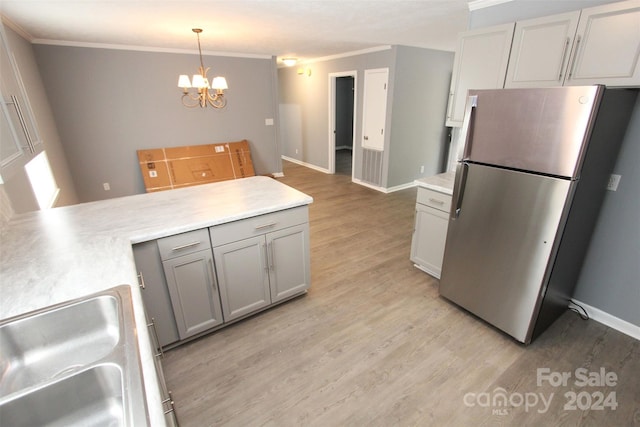 kitchen featuring a notable chandelier, gray cabinetry, stainless steel refrigerator, pendant lighting, and light hardwood / wood-style flooring