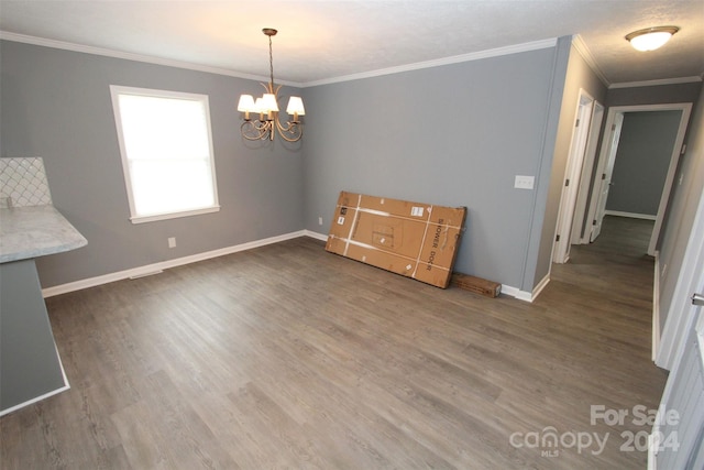 unfurnished dining area with dark hardwood / wood-style flooring, an inviting chandelier, and ornamental molding