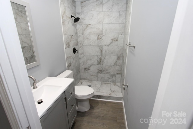 bathroom with toilet, vanity, hardwood / wood-style floors, and tiled shower