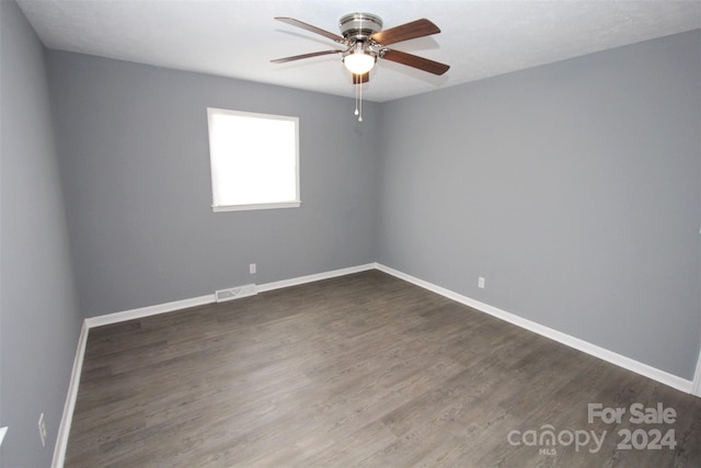 spare room with dark wood-type flooring and ceiling fan