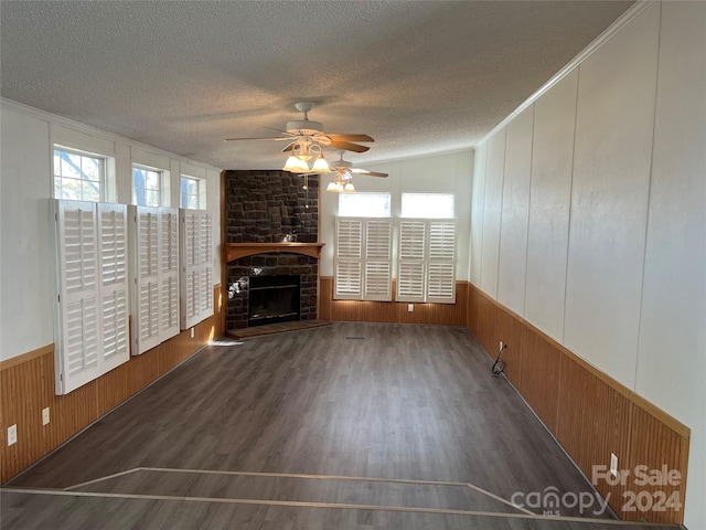 unfurnished living room featuring lofted ceiling, a stone fireplace, dark hardwood / wood-style floors, ceiling fan, and a textured ceiling