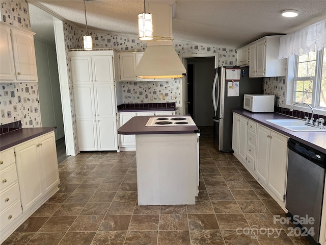 kitchen with a center island, lofted ceiling, hanging light fixtures, a textured ceiling, and stainless steel appliances