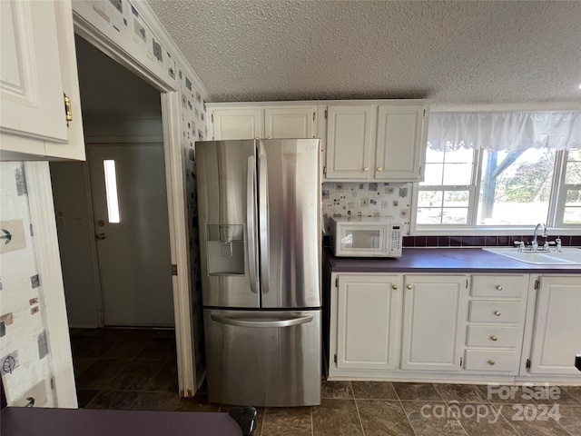 kitchen with sink, stainless steel refrigerator with ice dispenser, crown molding, a textured ceiling, and white cabinets