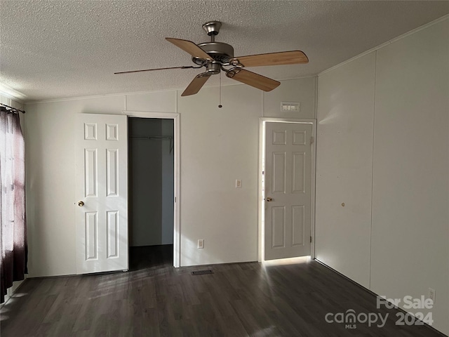 empty room with dark hardwood / wood-style floors, lofted ceiling, and a textured ceiling