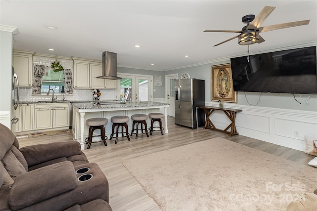 living room featuring ornamental molding, light hardwood / wood-style flooring, ceiling fan, and sink