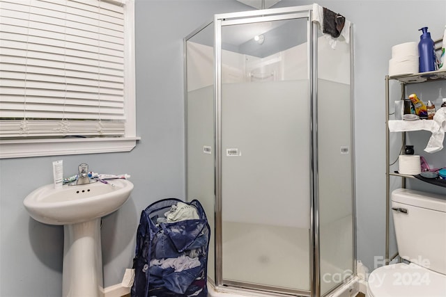 bathroom with an enclosed shower, sink, and toilet