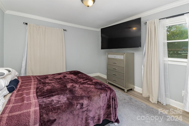 bedroom featuring light wood-type flooring and crown molding