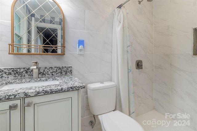 bathroom featuring walk in shower, vanity, toilet, and tile walls