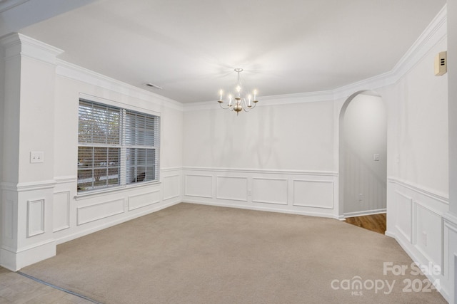 carpeted spare room with an inviting chandelier and crown molding