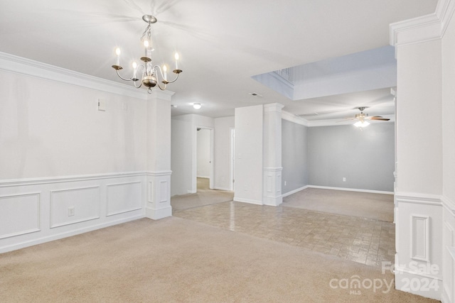 empty room featuring decorative columns, light carpet, ornamental molding, and ceiling fan with notable chandelier