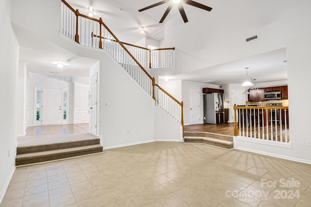 interior space featuring tile patterned flooring, ceiling fan, and a high ceiling