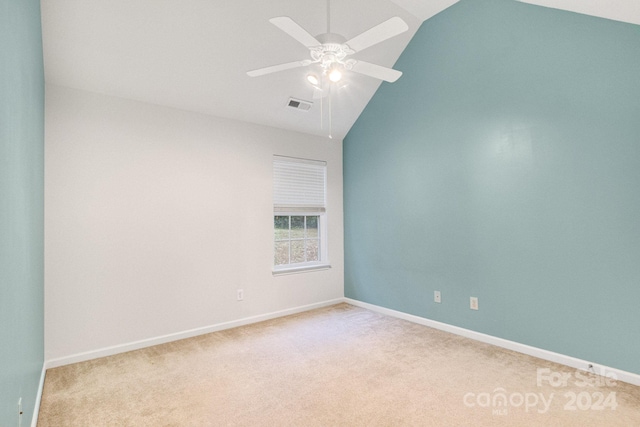 empty room with lofted ceiling, light colored carpet, and ceiling fan