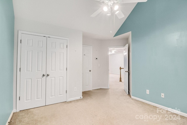 unfurnished bedroom featuring light carpet, ceiling fan, vaulted ceiling, and a closet