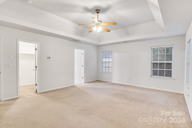 carpeted spare room featuring ceiling fan and a tray ceiling