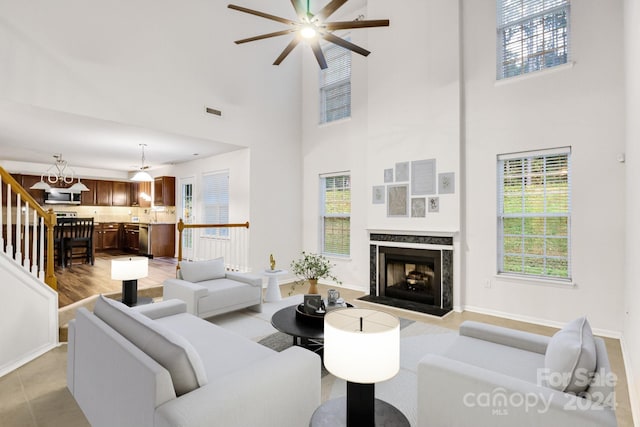 living room with a towering ceiling, ceiling fan, and a premium fireplace