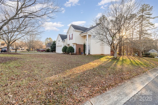 view of side of property featuring a garage and a lawn