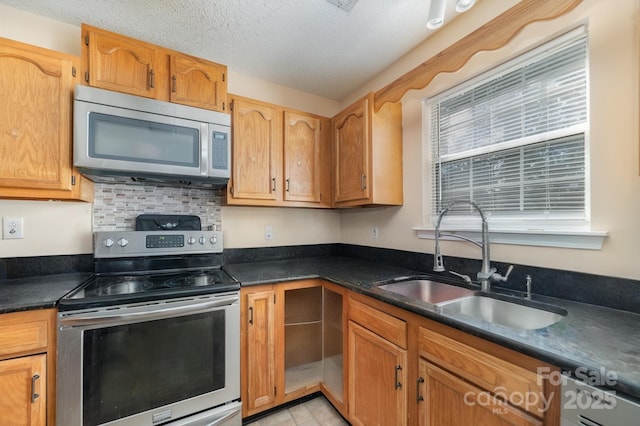 kitchen with sink, decorative backsplash, a textured ceiling, and appliances with stainless steel finishes