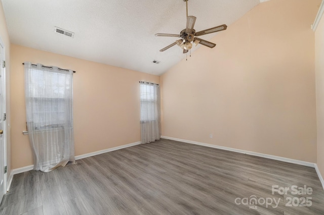 spare room featuring hardwood / wood-style floors, vaulted ceiling, a textured ceiling, and ceiling fan