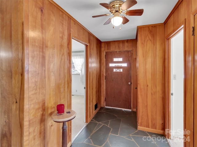 foyer with wooden walls and ceiling fan