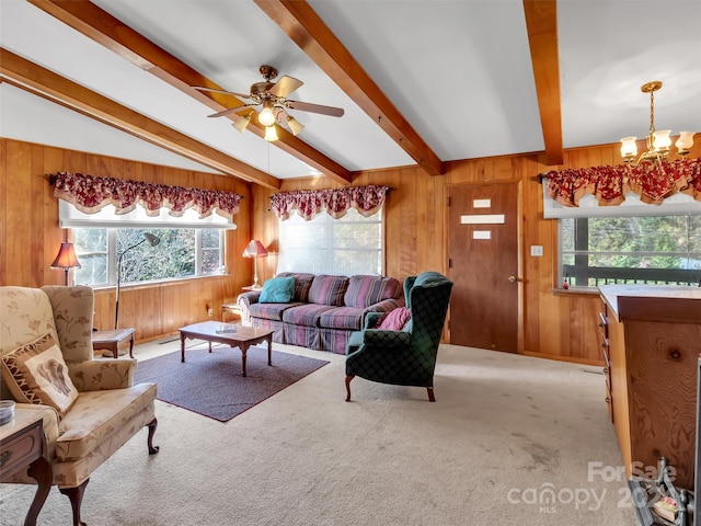 living room featuring lofted ceiling with beams, wooden walls, light carpet, and ceiling fan with notable chandelier