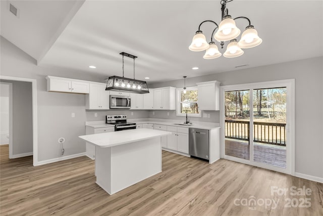 kitchen with white cabinets, a kitchen island, decorative light fixtures, stainless steel appliances, and sink