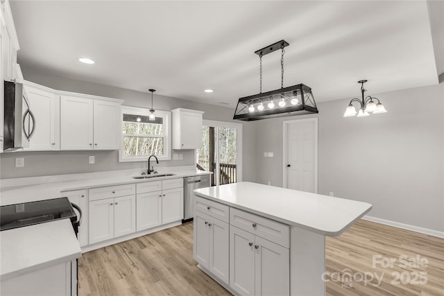 kitchen featuring stainless steel appliances, a kitchen island, decorative light fixtures, and sink