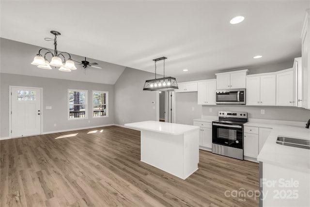 kitchen with white cabinets, stainless steel appliances, a center island, and sink