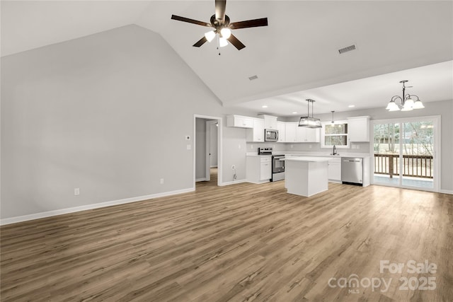 unfurnished living room with light hardwood / wood-style floors, high vaulted ceiling, and ceiling fan with notable chandelier