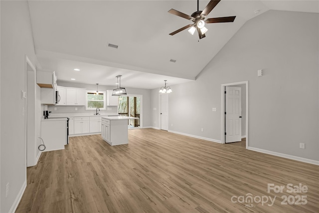 unfurnished living room with ceiling fan with notable chandelier, sink, light hardwood / wood-style flooring, and high vaulted ceiling